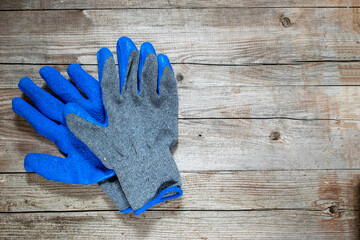 Construction rubberized gloves on a grey wooden background. Blue protective rubber gloves for construction and operation with caustic substances or for repair. Garden gloves for work in the garden.