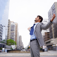 A love for the city. A contented young businessman standing in the city with his eyes closed and his arms raised.