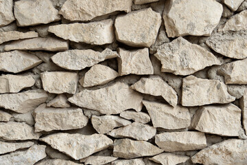 Primitive stonework. An ancient wall made of rough stones and cement. Gray stone background.