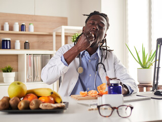 young nutritionist take a break in office and eat a tangerine