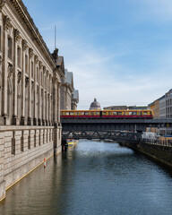 Naklejka premium Berlin, Germany: S-Bahn train passing by on the bridge of Museum Island. The building of Humboldt Forum on the background