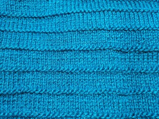 Close-up of a blue wool knitted fabric. Crocheted texture background.