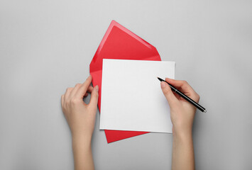 Woman writing letter on grey background, top view