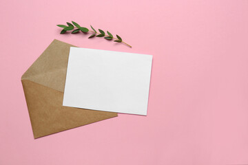 Brown envelope with blank letter and plant on pink background, flat lay. Space for text