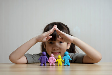 Naklejka premium cute asian girl Build a plasticine figure of mom, dad and child and sibling. family home concept and family relationships. Family warmth and love. Children's creativity and learning