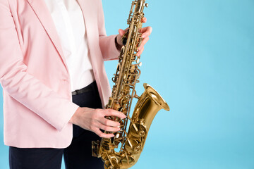 Fototapeta na wymiar Woman with saxophone on light blue background, closeup. Space for text