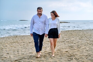 Happy middle-aged couple walking together on the beach.