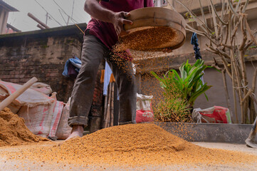 Howrah, West Bengal, India - 6th January 2020 : Indian labour separating sand and gravel manually using a sieve, for using the sand for cementing work, Image shot from low angle.