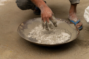 Indian labour mixing cement and water manually on bucket using bare hands. Stcok image.