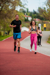 Athletic couple of sprinters run on running track at stadium, success