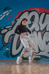 Attractive young woman doing breakdance move over graffiti background