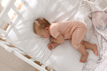 Cute little baby sleeping in soft crib at home, top view