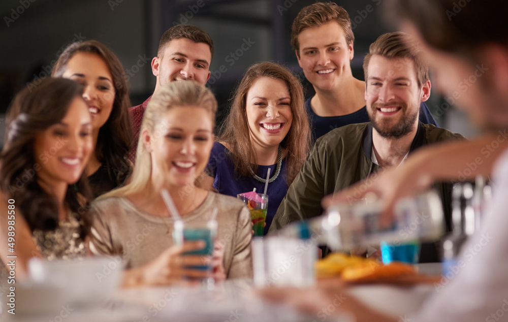 Poster drinks and a show. shot of a happy group of friends having drinks at a bar together.