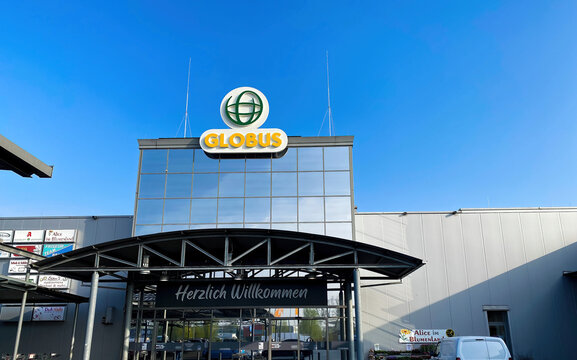 Viersen, Germany - April 14. 2022: View on sign with logo lettering of globus supermarket chain over store entrance against clear blue sky