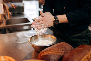 Chef with flour. Handsome baker in uniform using flour to make bread or croissant in bakery