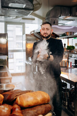 Chef with a Flour. Handsome baker in uniform brightly slamming flour for cooking bread or croissant...