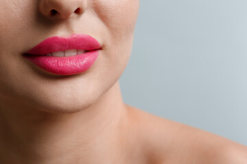 Closeup view of woman with beautiful lips on light grey background. Space for text