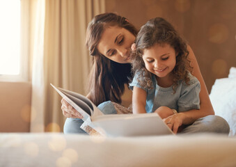 This is the best story ever. Shot of a happy mother and daughter at home reading a storybook on the...