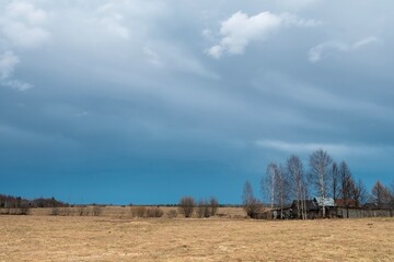 a lonely wooden house in a field against a cloudy sky