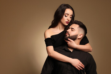 Handsome bearded man with sexy lady on light brown background. Space for text