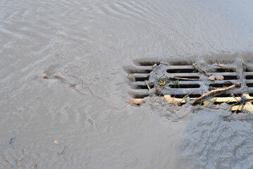 Dirty, clogged iron grate of urban rain sewer, drainage during rainstorm outdoors