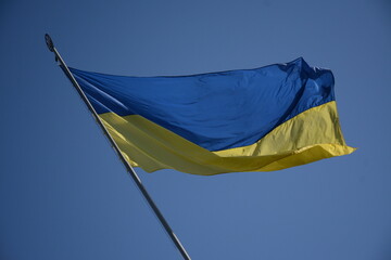 Ukrainian  yellow blue national flag with trident emblem waving in wind against sky. National flag of Ukraine on sunny day