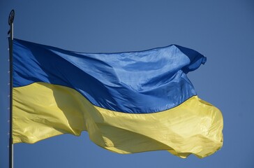 The Ukrainian flag flutters in the wind on a sunny day. Flag of Ukraine against the blue sky. National symbol of freedom and independence.