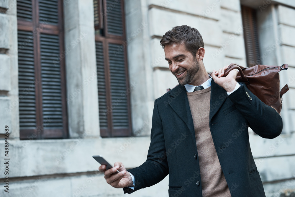 Poster Staying in touch even when hes out and about. Cropped shot of a handsome businessman using his cellphone while about town.