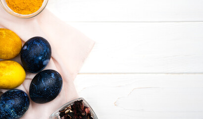 Easter eggs painted blue and yellow color on a white wooden table. Coloring Easter eggs with natural dyes. Top view. Copy space. Banner.
