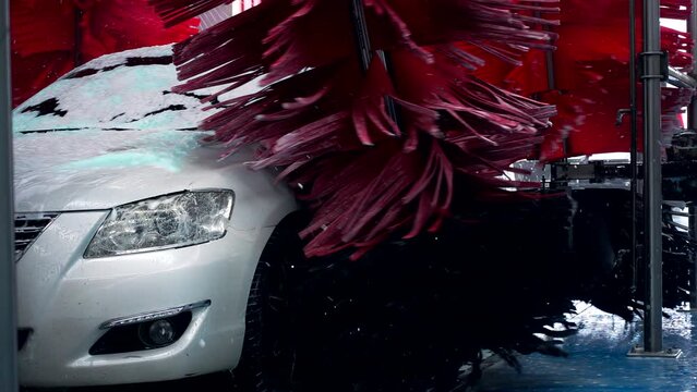 White car moving though automatic car wash machine. The brush moving to clean the car. Slow motion shot