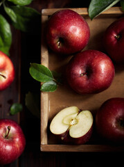 Ripe red apples in wooden box. Top view with space for your text. Ripe red apples in a wooden box. Top view with space for text. Apples whole and cut in half, apple leaves. Harvest from the garden.