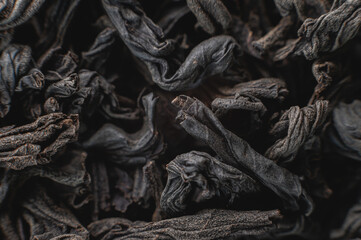 Extreme macro Black loose leaf tea as a background. Texture of dry black tea leaves in shallow depth of field. Dark background. macro mode. black leaf tea closeup