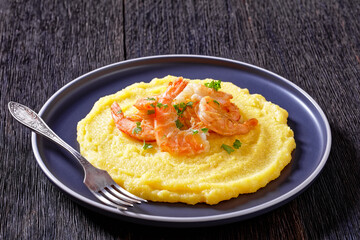 polenta with fried shrimps on plate, top view