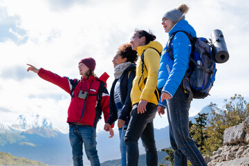 group of young hikers on top of the mountain enjoying the view and contemplating nature - selective...