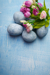 Fototapeta na wymiar Painted Easter eggs on blue background with pink flowers. Spring holiday symbol. Copy space. Vertical shot