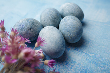 Painted Easter eggs on blue background with purple flowers. Spring holiday symbol. Copy space. Close up shot
