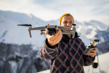 Young man video maker flies a drone in the snowy mountains, launches a drone from his hands. Creating travel content from a drone
