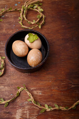 Black bowl with brown colored Easter eggs on rustic background. Spring, Easter concept. Top view, copy space, vertical shot