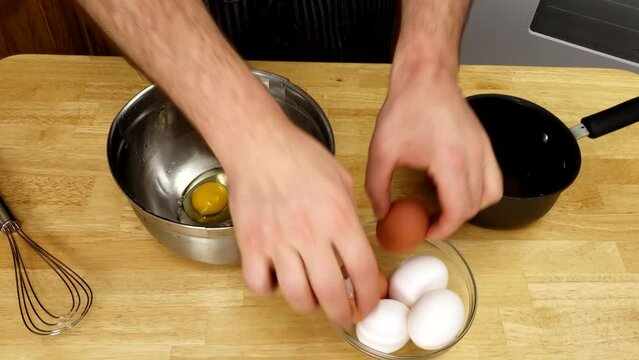 Home cooking - Cracking or adding whole eggs into stainless steel bowl in preparation of adding other ingredients to whisked to make omelet batter.
