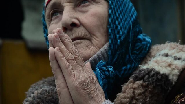A woman prays for an end to the war. Ukrainian grandmother prays during the war.War in Ukraine. Ukrainian refugees. Peace concept. Stop the war. Russian aggression against Ukraine