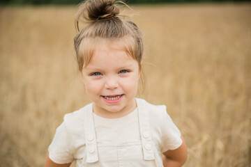 Portrait a little girl walks in a wheat field