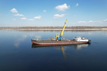 An old dry-cargo ship is anchored under sand loading on the Volga