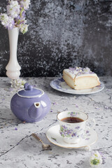 still life with black tea and cheese cake, spring bouquet,delicate lilac flowers
