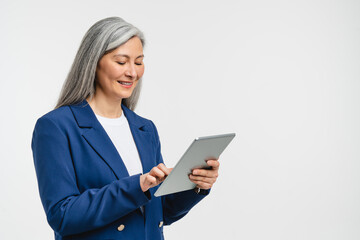 Fototapeta premium Happy confident mature middle-aged businesswoman teacher tutor freelancer bank manager employee CEO boss in formal suit working on digital tablet, searching information online, watching webinars