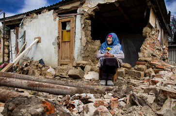 A woman prays in front of a destroyed house during the war. Ukrainian woman on the ruins of a war-torn house. War in Ukraine. Bombardment of Ukrainian cities. Ukrainian refugees.