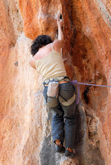 Rock climbing in Olympos. A Caucasian young woman climbs a rout. Antalya Province, Turkey.