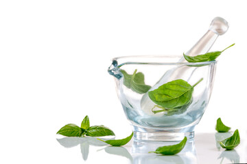 Image of basil in a glass mortar isolated on white background.