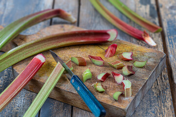 Close-up of rhubarb cut into small pieces with a knife on a cutting.