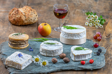 Obraz na płótnie Canvas Four French cheeses from Normandy laid on a slate platter in front.