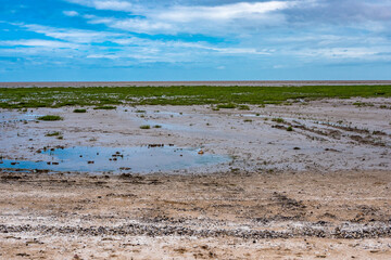 Strand mit Wolken bei Ebbe